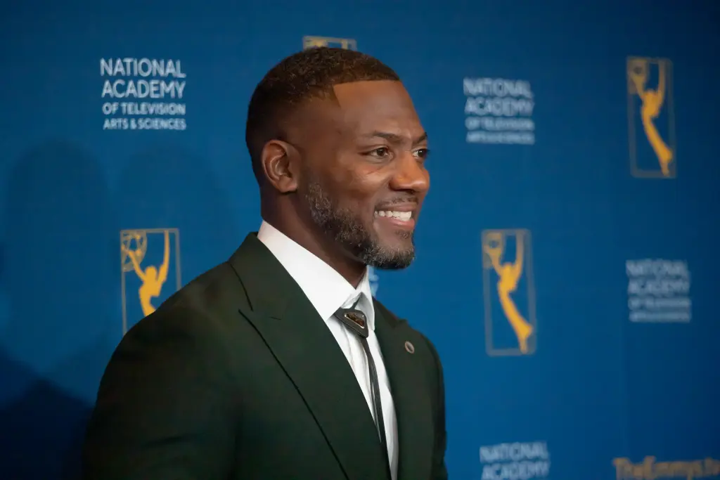 Ryan Clark speaking at a sports event in formal attire