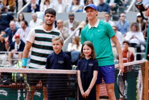 Carlos Alcaraz and Jannik Sinner pose with young fans before the French Open 2025 final match at Roland Garros.